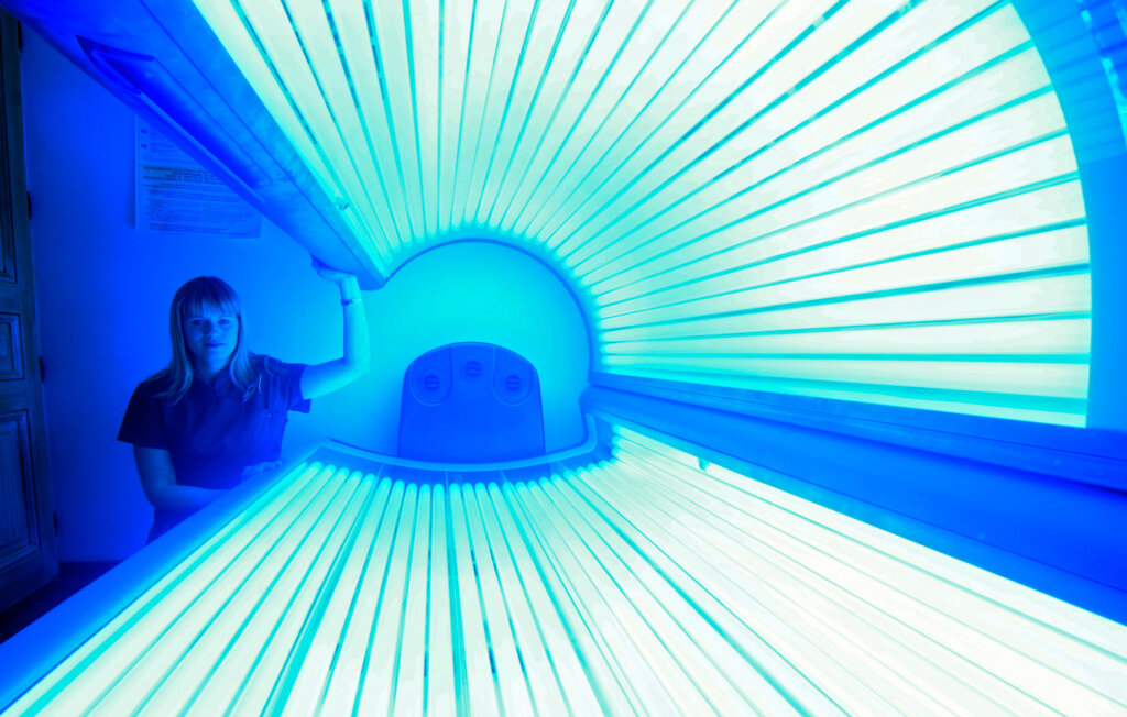 An employee in a beauty salon poses with a sunbed