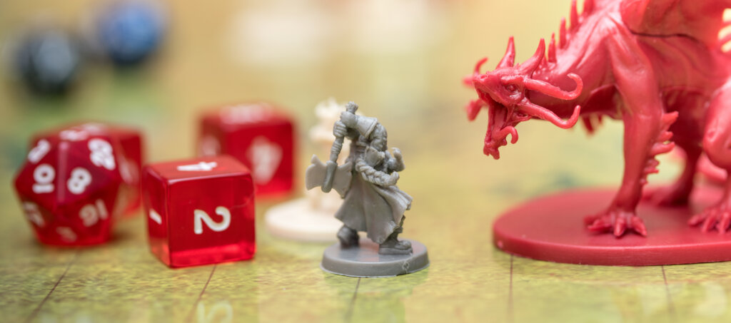 Detail of two miniatures fighting on the battlefield of the role-playing game of dungeons and dragons. Game dices next to the figures.